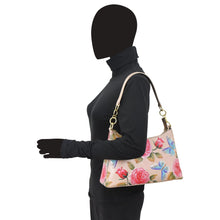 Load image into Gallery viewer, A person with a digitally anonymized face wearing a black outfit and gloves, carrying an Anuschka floral print genuine leather hobo bag - Hobo With Chain Strap 707.
