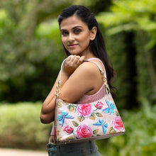 Load image into Gallery viewer, A woman wearing a pink top and carrying an Anuschka genuine leather floral Hobo With Chain Strap - 707 purse looking over her shoulder.
