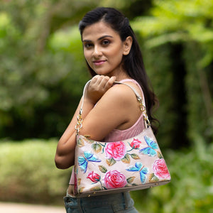 A woman wearing a pink top and carrying an Anuschka genuine leather floral Hobo With Chain Strap - 707 purse looking over her shoulder.