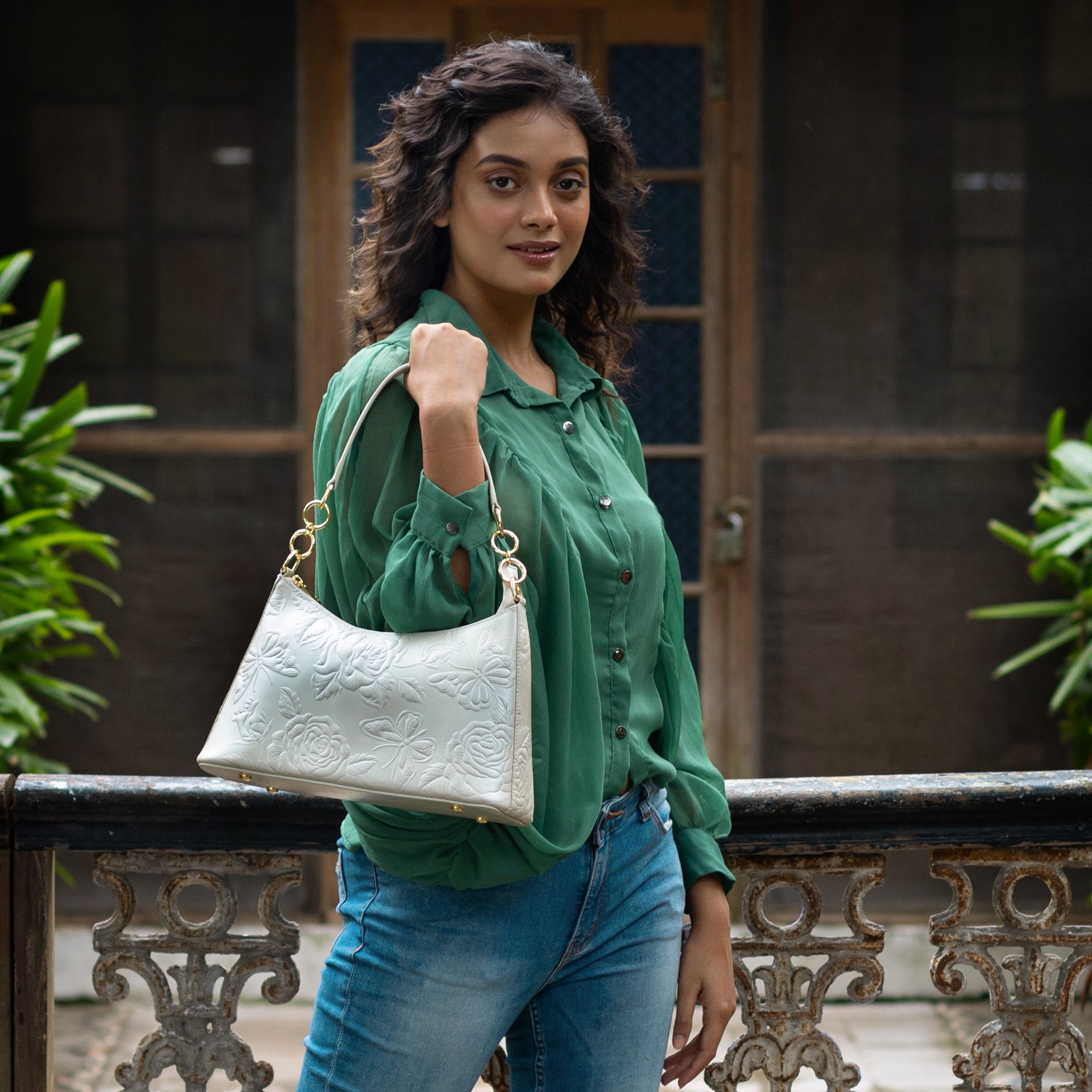 A woman with an Anuschka Hobo With Chain Strap - 707 shoulder bag posing outdoors.