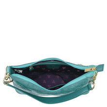 Load image into Gallery viewer, Open Anuschka turquoise genuine leather exterior handbag with an empty interior and floral pattern lining.
