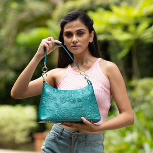 Woman posing with a teal Anuschka embossed genuine leather hobo bag with chain strap - 707.