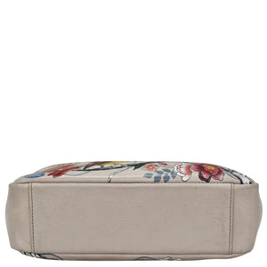 A beige leather cosmetic bag with a floral pattern on top, the Anuschka Satchel With Crossbody Strap - 708.