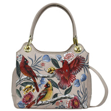 Load image into Gallery viewer, A beige leather Anuschka handbag with a colorful bird and floral print and gold-tone hardware.
