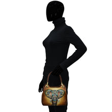 Load image into Gallery viewer, Silhouetted figure with a Satchel With Crossbody Strap - 708 handbag by Anuschka featuring an elephant design.
