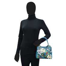 Load image into Gallery viewer, Mannequin in a black turtleneck holding an Anuschka satchel with crossbody strap - 708.
