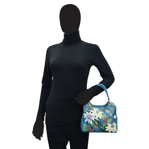 Mannequin in a black turtleneck holding an Anuschka satchel with crossbody strap - 708.