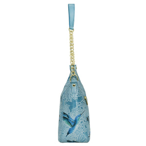 A blue floral-patterned leather Zip-Top Shoulder Hobo - 709 by Anuschka with a gold chain link detail strap and a blue ribbon handle.