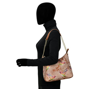 Side profile of a mannequin dressed in black and carrying an Anuschka Zip-Top Shoulder Hobo - 709 with hand-painted artwork.