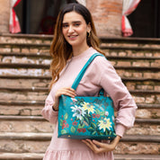 A woman holding a blue leather Medium Everyday Tote - 710 by Anuschka.