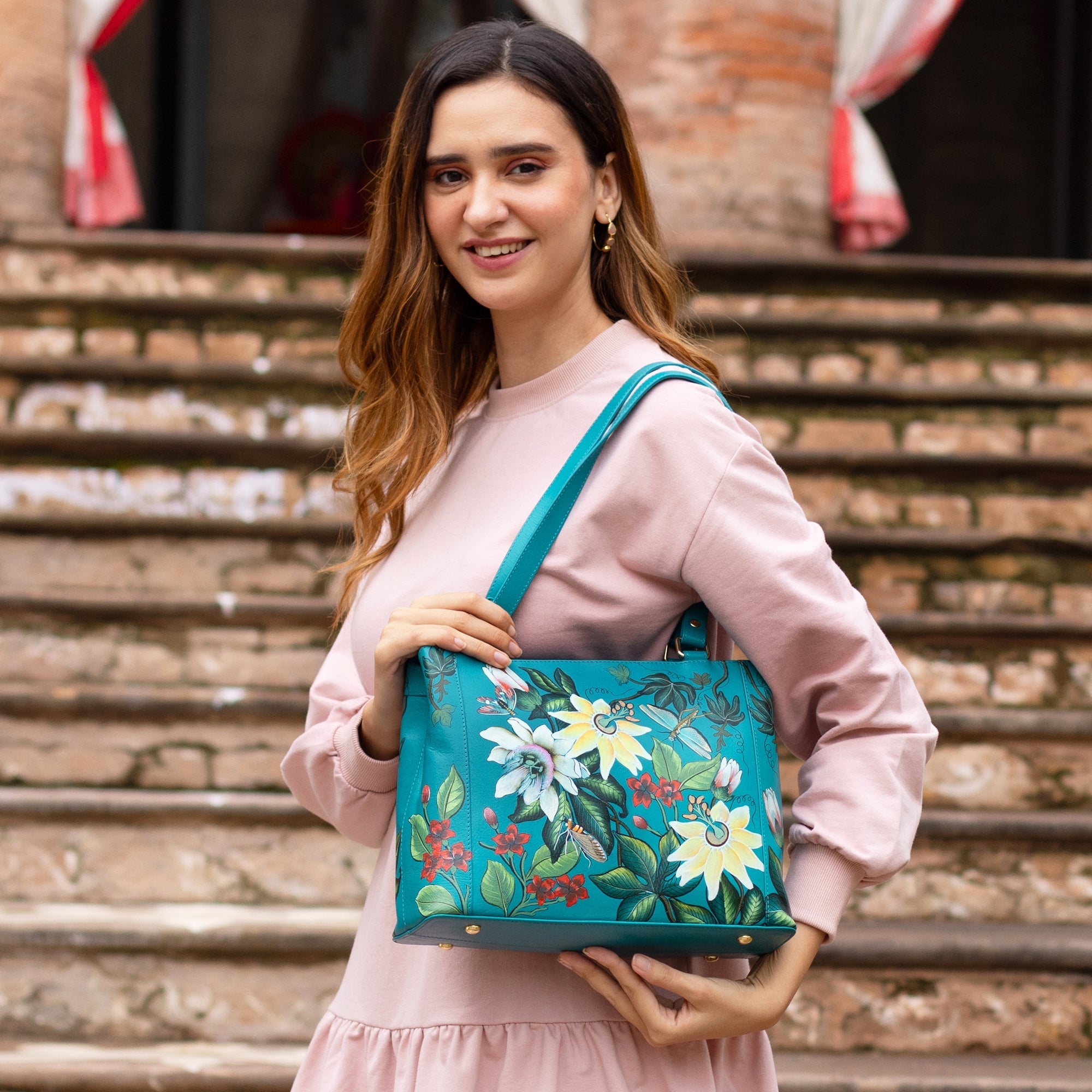 A woman holding a blue leather Medium Everyday Tote - 710 by Anuschka.