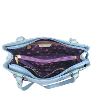 Light blue Anuschka genuine leather handbag with open interior showing purple lining and compartments.