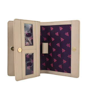 Beige genuine leather wallet open to reveal a purple floral interior with slots for cards and a visible sunglasses picture, the Anuschka 4 in 1 Organizer Crossbody - 711.