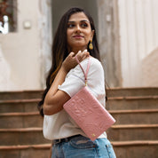 Woman with an Anuschka genuine leather pink embossed 4 in 1 Organizer Crossbody - 711 standing on stairs looking upwards.