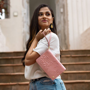 Woman with an Anuschka genuine leather pink embossed 4 in 1 Organizer Crossbody - 711 standing on stairs looking upwards.
