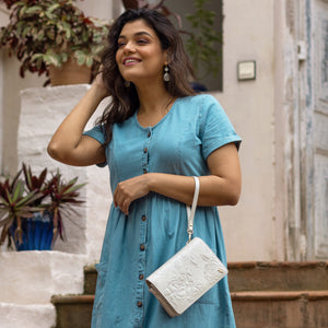 A woman in a blue dress smiling and posing with an Anuschka 4 in 1 Organizer Crossbody - 711 shoulder bag.