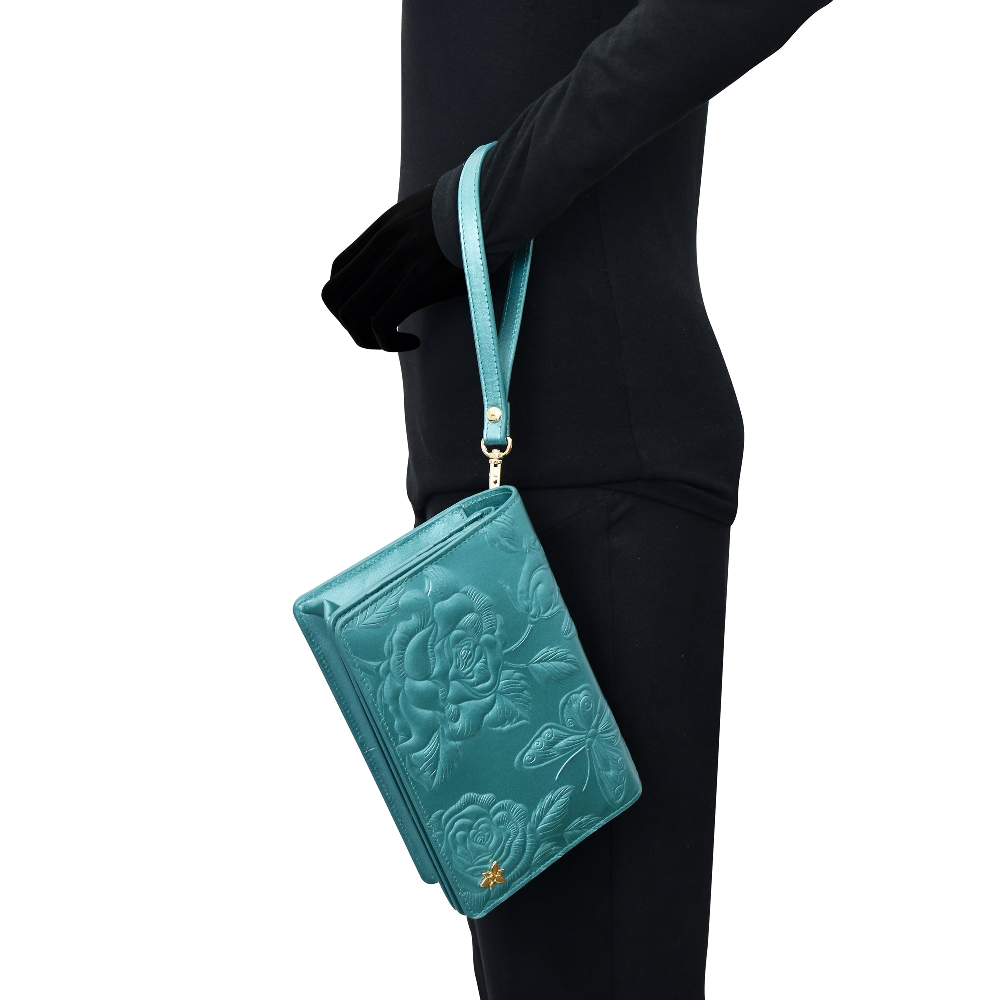 A person in a black outfit holding a Anuschka 4 in 1 Organizer Crossbody - 711 with a wrist strap.