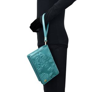 A person in a black outfit holding a Anuschka 4 in 1 Organizer Crossbody - 711 with a wrist strap.