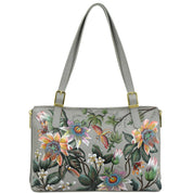 The Anuschka Expandable Shopper Tote - 712 is a spacious gray handbag adorned with hand-painted floral and butterfly designs in vibrant colors. Made from genuine leather, this bag features two straps with gold buckles.