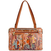 The Expandable Shopper Tote - 712 by Anuschka is a spacious handbag crafted from genuine tan leather. It features two handles and is adorned with hand-painted Egyptian artwork depicting historical figures and vibrant symbols. Complete with a front zipper pocket and gold hardware, it effortlessly blends style and convenience.