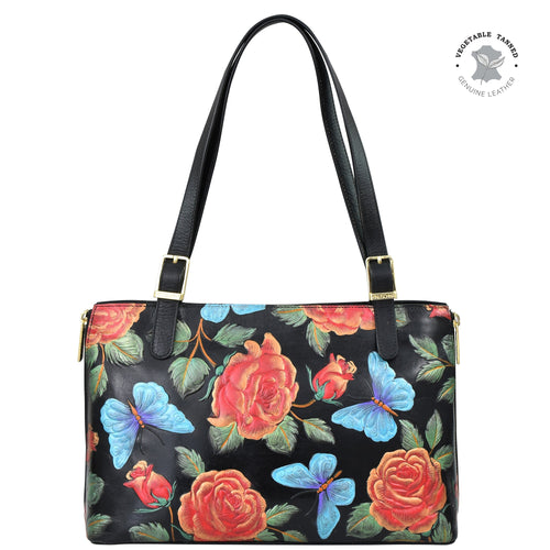 Anuschka's Expandable Shopper Tote - 712 is a black leather tote bag showcasing exquisite hand-painted artwork of red roses and blue butterflies. This roomy tote features two black straps embellished with gold-tone buckle accents, and bears a stamp indicating it is made from genuine leather.