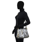 A mannequin dressed in black showcases the Anuschka Crossbody Sling Bag - 713, a genuine leather shoulder bag adorned with a cityscape design featuring prominent skyline elements and an adjustable crossbody strap.