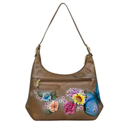 The Anuschka Slim Shoulder Hobo - 714 is a genuine leather bag adorned with painted floral designs and a striking large blue butterfly. It includes a front zipper pocket and a shoulder strap, making it an ideal everyday bag.