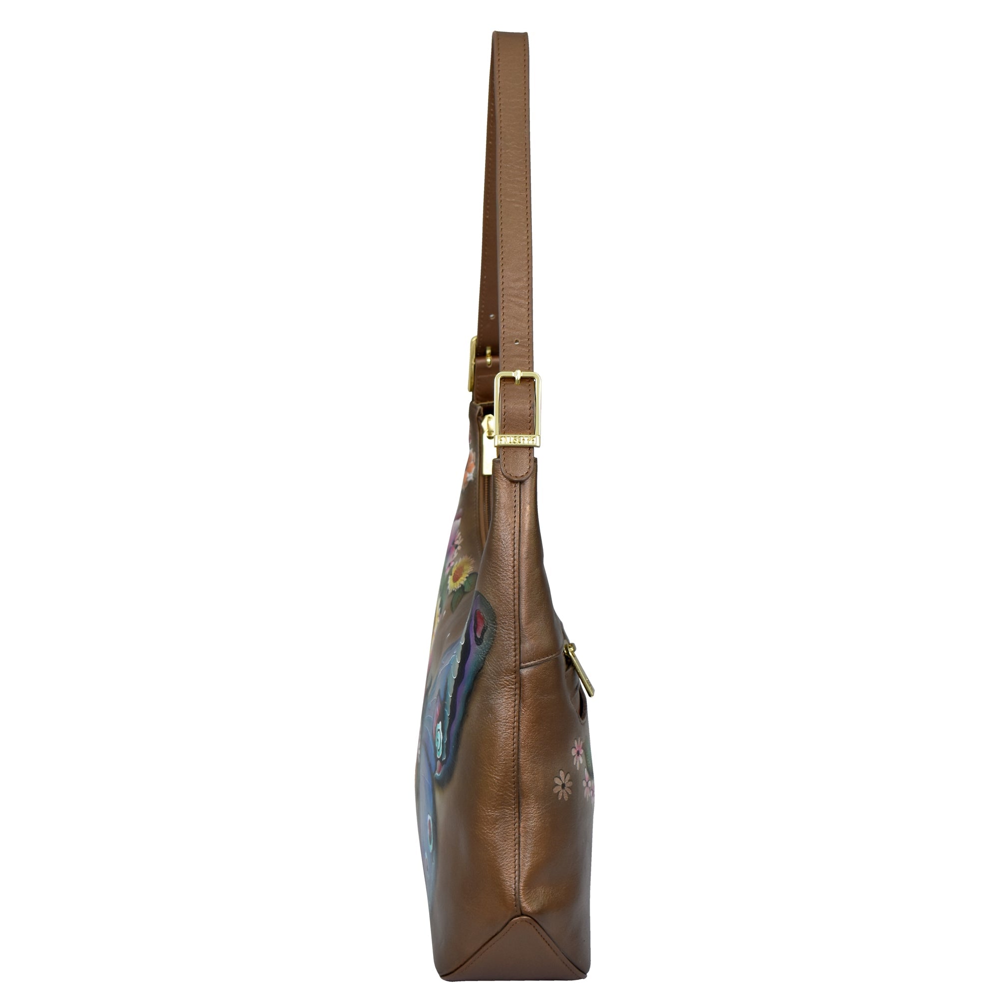 Side view of the Slim Shoulder Hobo - 714 by Anuschka, a brown genuine leather shoulder bag adorned with floral patterns and featuring a gold buckle on the strap.