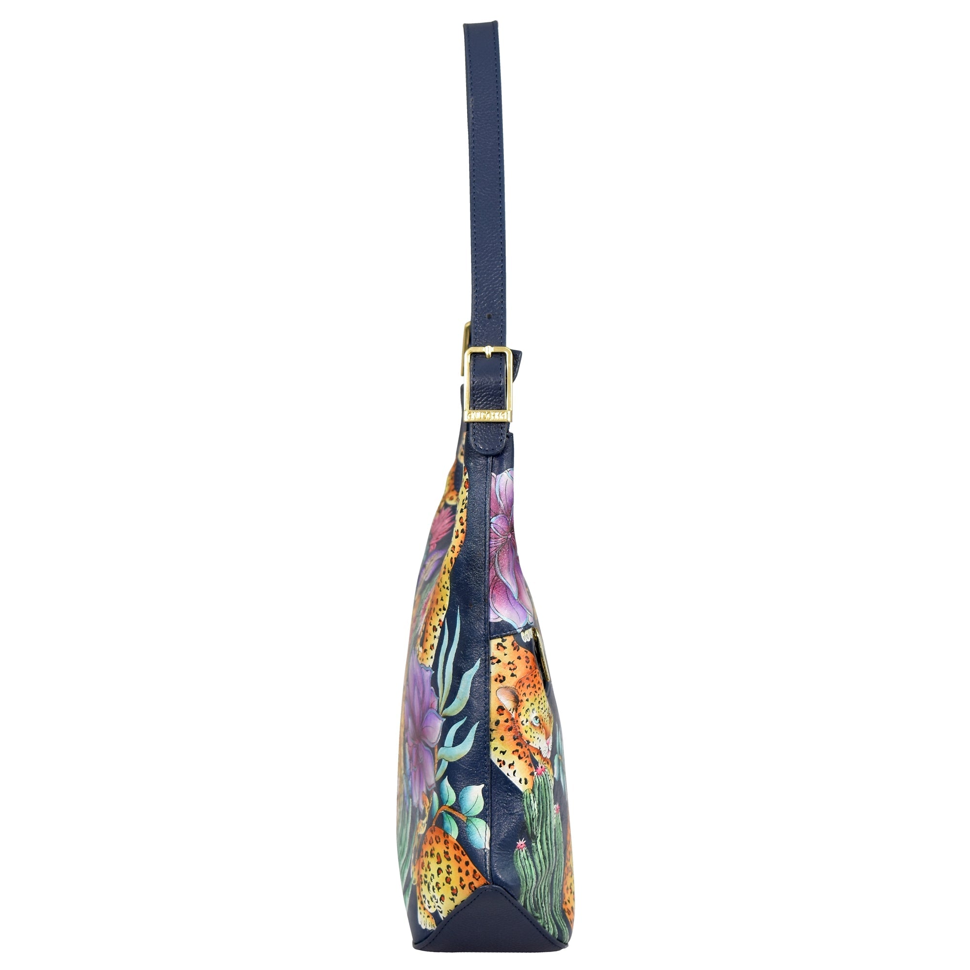 Side view of the Slim Shoulder Hobo - 714, a blue genuine leather handbag by Anuschka, adorned with a jungle-themed print featuring leopards and foliage. This modern Hobo bag showcases gold hardware and a blue strap, making it an ideal choice for everyday use.