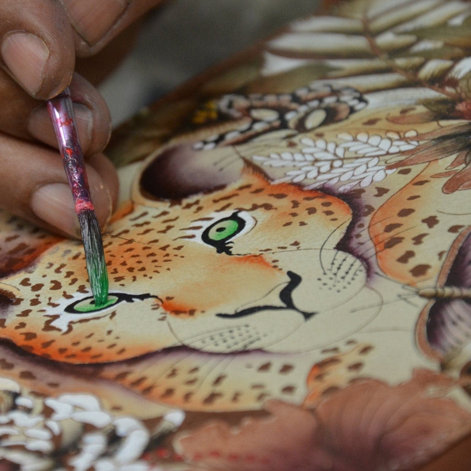 An artist's hand painting details on a Anuschka Classic Hobo With Studded Side Pockets - 433.