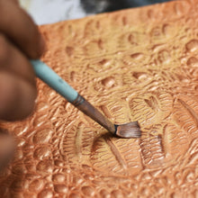 Load image into Gallery viewer, Applying hand-painted artwork to an Anuschka Three Fold Wallet - 1150 with a brush.

