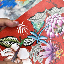 Load image into Gallery viewer, A person painting a floral design on a textured genuine leather Anuschka Bucket Backpack - 685.
