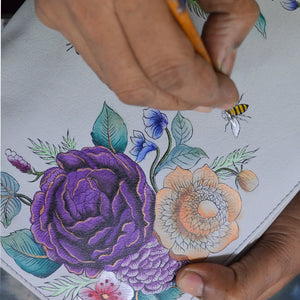 Hand drawing colorful flowers and a bee on an Anuschka Two-Fold Small Organizer Wallet - 1166 with RFID protection.