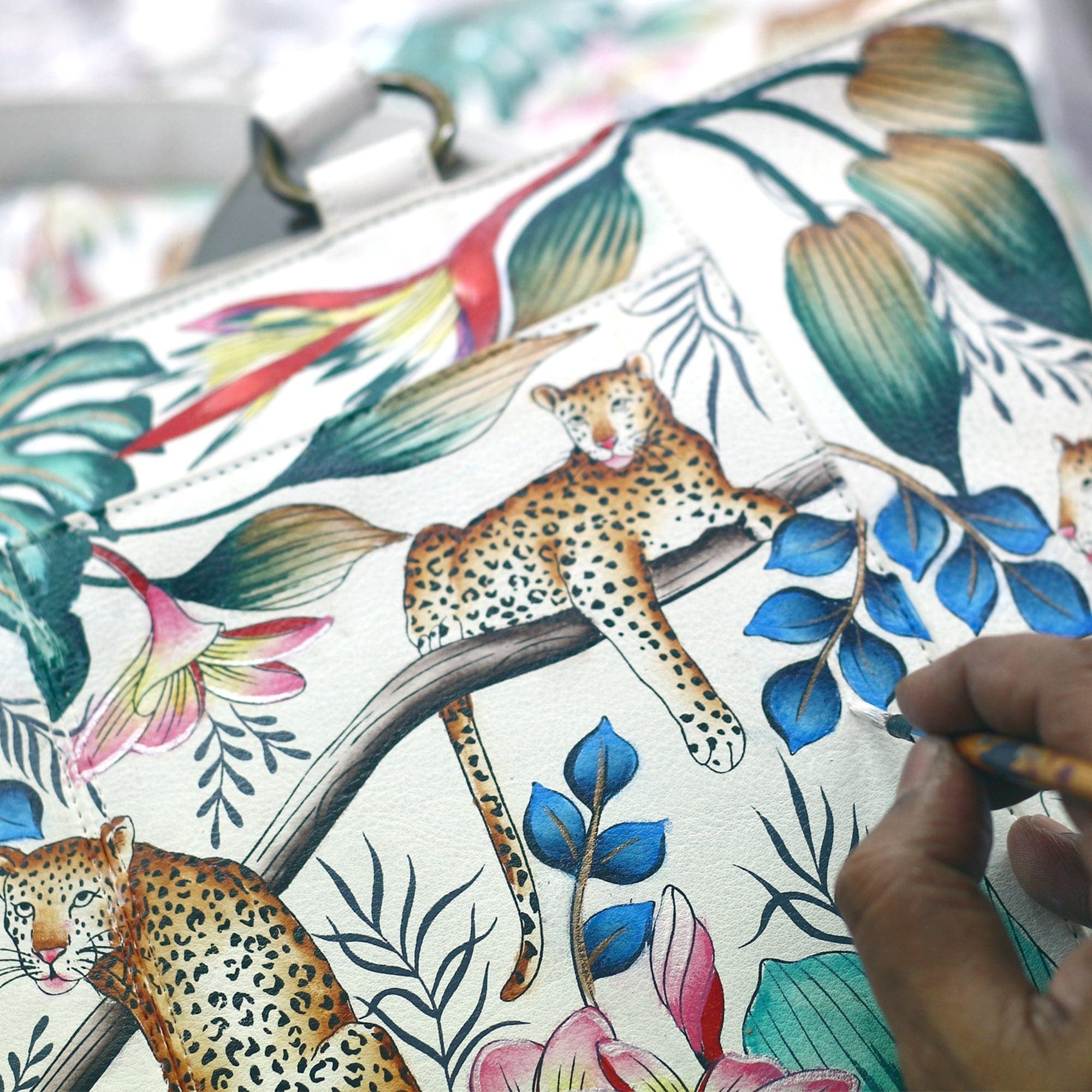A close-up view of an Anuschka Zip Around Travel Organizer - 668 handbag with a colorful leopard and floral print design, crafted from leather.