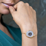 Close-up of a woman’s hand wearing a Sliced Quartz Bracelet from Vanya Lara, touching her lips.