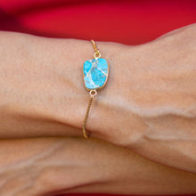 Load image into Gallery viewer, A gold-plated, Mojave Glory Bracelet by Vanya Lara on a wrist against a red background.
