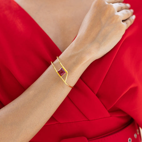 A woman wearing a red dress with a Golden Ratio Bracelet featuring a natural gemstone by Vanya Lara.
