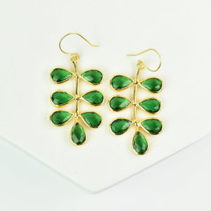 A pair of Foliage Earrings by Vanya Lara with green gemstone inlays of unique design displayed on a white background.