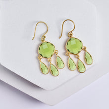 Load image into Gallery viewer, Triple Dew Drop Earrings by Vanya Lara with green gemstones in a hydro stone setting on a white display stand.
