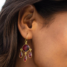 Load image into Gallery viewer, A close-up of a woman&#39;s ear wearing Vanya Lara&#39;s Triple Dew Drop Earrings with red gemstones in a gold setting.
