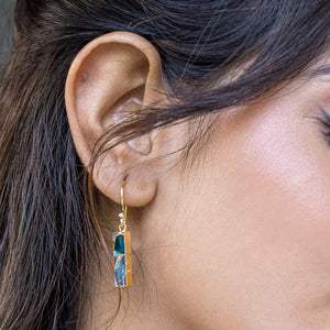 A close-up of a woman's ear wearing a dangling earring with a Mojave turquoise stone: Mojave Brick Earrings by Vanya Lara - VER0008.