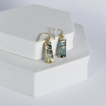 Load image into Gallery viewer, A pair of rectangular Mojave Brick earrings by Vanya Lara displayed on a white stand.
