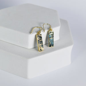 A pair of rectangular Mojave Brick earrings by Vanya Lara displayed on a white stand.