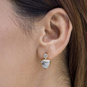 A woman wearing Triangle Drop Earrings by Vanya Lara with turquoise stones and gold plating.