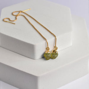 Pendulum Thread Earrings with green gemstone beads on a white display block by Vanya Lara.