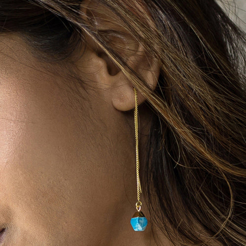 A close-up view of a woman's ear with a Pendulum Thread Earrings - VER0013 by Vanya Lara featuring gemstone beads.