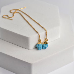 Pendulum Thread Earrings with blue gemstone beads pendants on a white display stand by Vanya Lara.