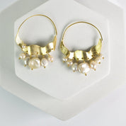 Crescent Moon Hoops Earrings adorned with pearls and small gold accents, displayed on a white surface by Vanya Lara.