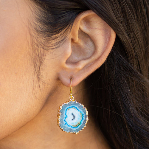 A woman wearing a Vanya Lara sliced quartz earring with a gold-plated edge.