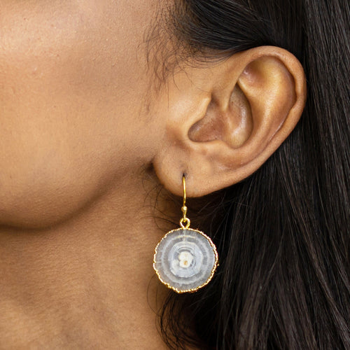 Close-up of a woman's ear wearing a Vanya Lara sliced quartz earring with gold-plated trim (product name: VER0017).